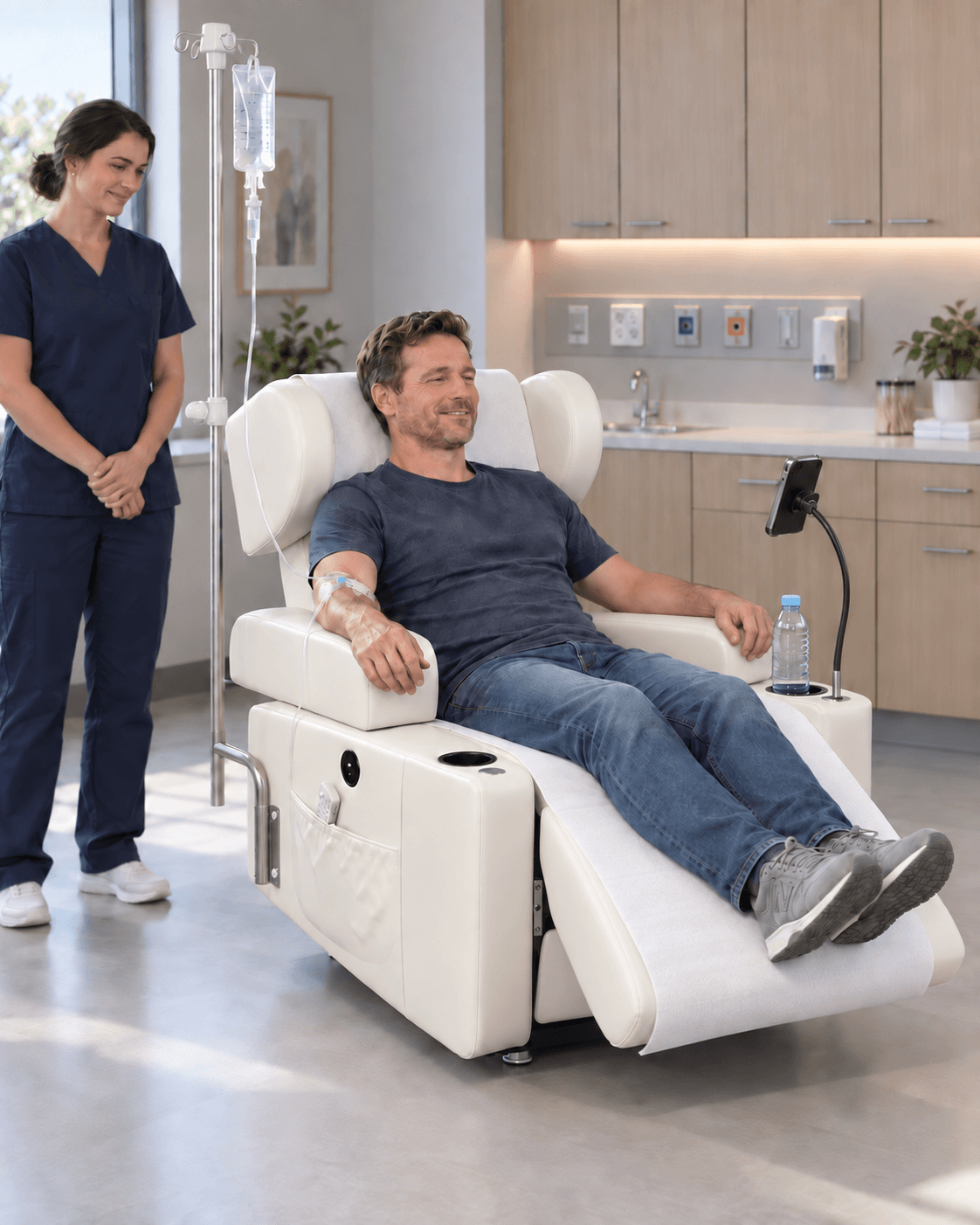 Adult man receiving an infusion in his right arm while seated in the EverCare RelaxIV, with a clinician nearby, a water bottle and a phone holder